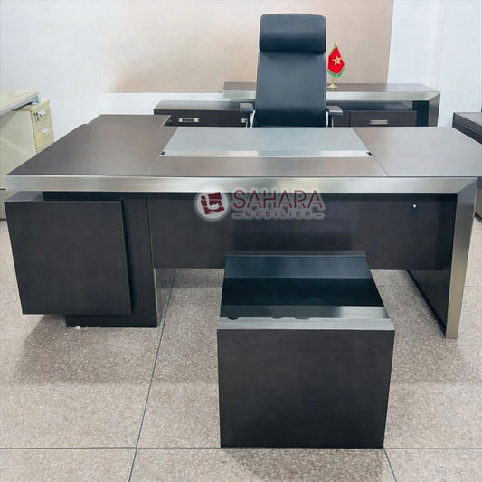Ce bureau de direction Sahara Mobilier se distingue par son design contemporain, ses lignes droites et son alliance harmonieuse entre MDF haut de gamme et finitions métalliques. Conçu pour les bureaux de direction, cabinets professionnels et administrations, il offre une image de prestige et de sérieux.

Son plan de travail spacieux assure un confort optimal au quotidien, tandis que la structure solide en MDF garantit stabilité et durabilité. Le voile de fond améliore l’ergonomie et l’esthétique, et le pass